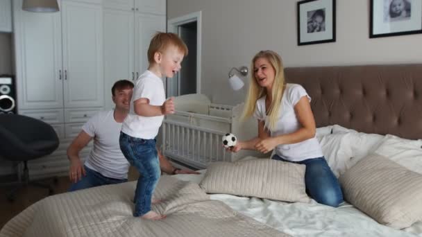 Eltern amüsieren sich mit ihrer kleinen Tochter im Bett. Familie verbringt Zeit am Morgen - Filmmaterial, Video
