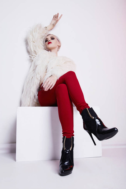 Beautiful blond young woman in fur and red trousers.winter fashion.Beauty sexy Model Girl with bob hair and make-up - Foto, Bild