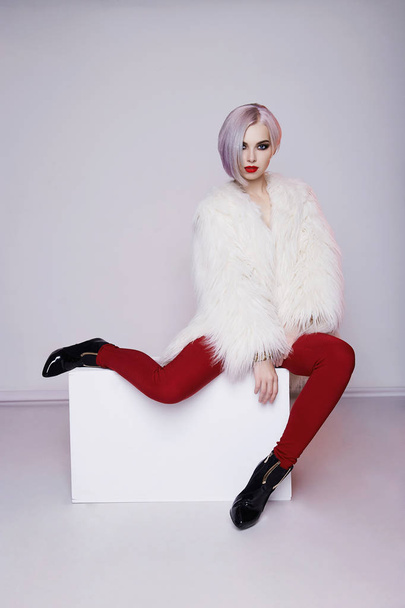 Beautiful blond young woman in fur and red trousers.winter fashion.Beauty sexy Model Girl with bob hair and make-up - Fotó, kép