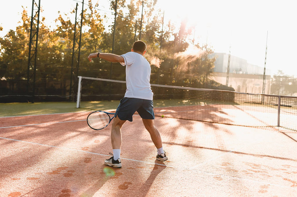  Man playing tennis in the morning in sunlight - Foto, afbeelding