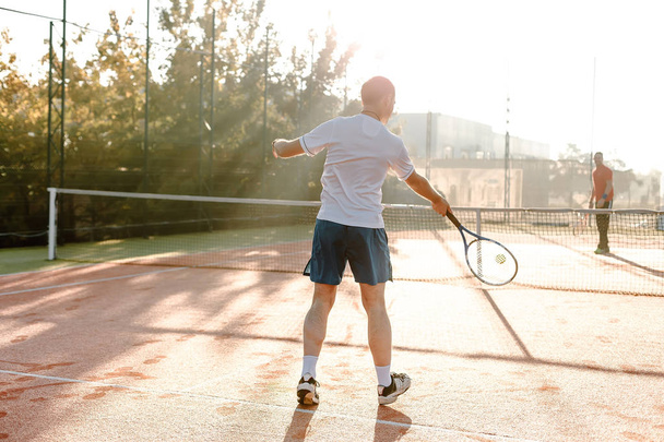  Homem jogando tênis de manhã à luz do sol
 - Foto, Imagem
