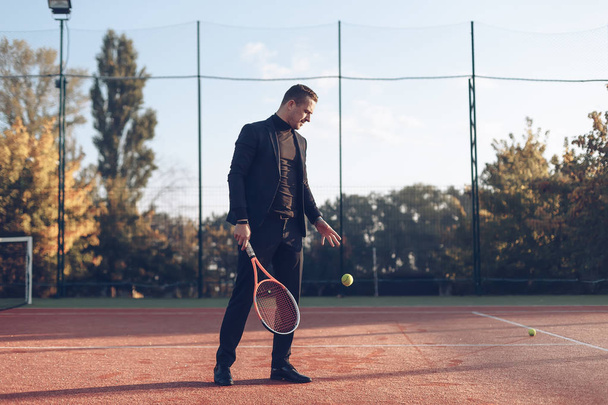 Businessman holding tennis racket throwing ball - Photo, Image