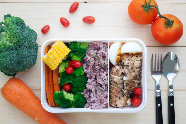 Directamente encima de la caja de almuerzo saludable con verduras, arroz, huevo cocido y pechuga de pollo, Primer plano sobre fondo de madera
 - Foto, Imagen
