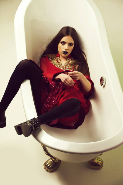 Beauty fashion portrait. woman in red dress with black lips in bath - Фото, изображение