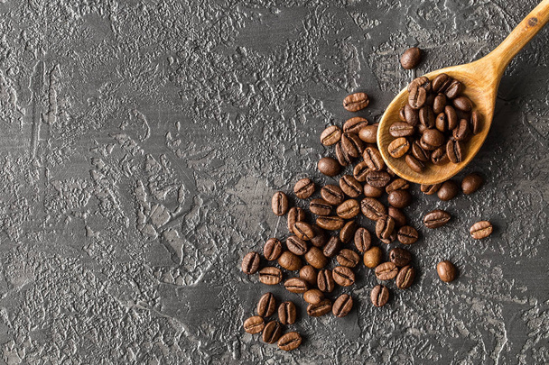 Roasted coffee beans in a wooden spoon on stone background. coffee beans on dark vintage background. Have a space for your text, Top view  - Фото, зображення
