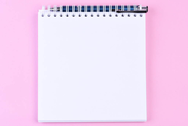 Κάτοψη του κενή σημείωση βιβλίο χαρτί με πένα σε ροζ φόντο - Φωτογραφία, εικόνα