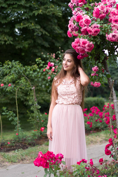 meisje en rozen, portret van een meisje in een roze tuin, rozen - Foto, afbeelding