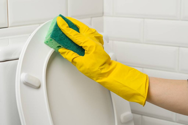 Mãos de mulher em luvas de borracha protetora amarela lavar o banheiro
. - Foto, Imagem
