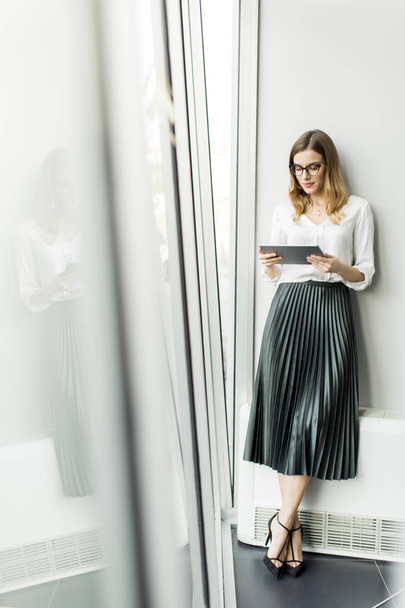 Mladá atraktivní žena správce pracuje na digitálním tabletu stoje v moderní kanceláři - Fotografie, Obrázek