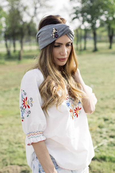 Portrait de jeune femme avec turban sur la tête et posant en plein air dans le parc
 - Photo, image