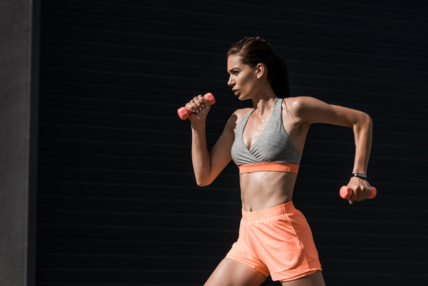 beautiful concentrated athletic girl running with dumbbells  - Photo, Image
