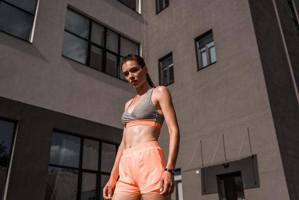 bottom view of young sportswoman posing in sportswear in city - Fotografie, Obrázek