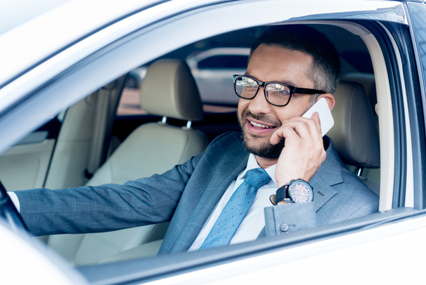 smiling businessman talking on smartphone while driving car  - 写真・画像