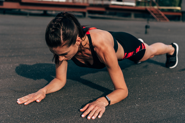 athletic woman doing plank on asphalt in city - Photo, Image