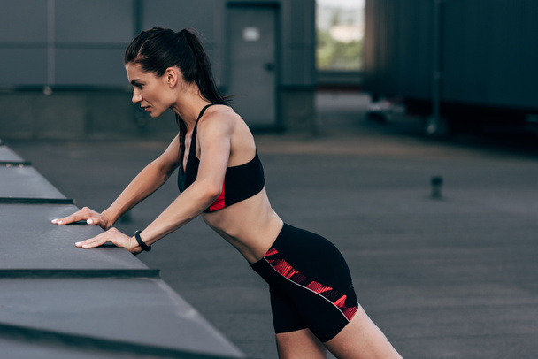 young concentrated sportswoman doing push up on roof   - Photo, Image