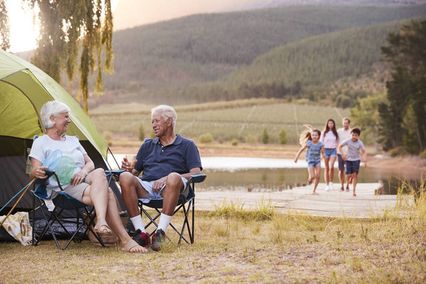 Multi Generation Family On Camping Trip By Lake Together - 写真・画像