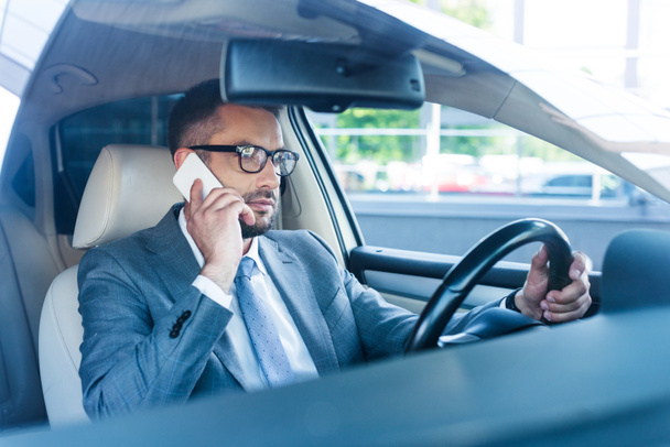 vue latérale de l'homme d'affaires parlant sur smartphone tout en conduisant la voiture
  - Photo, image