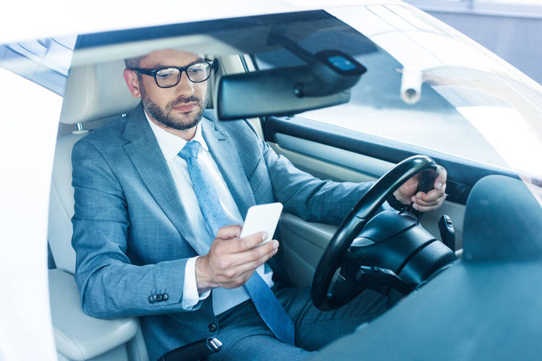 portrait of businessman with smartphone driving car  - Foto, Imagem