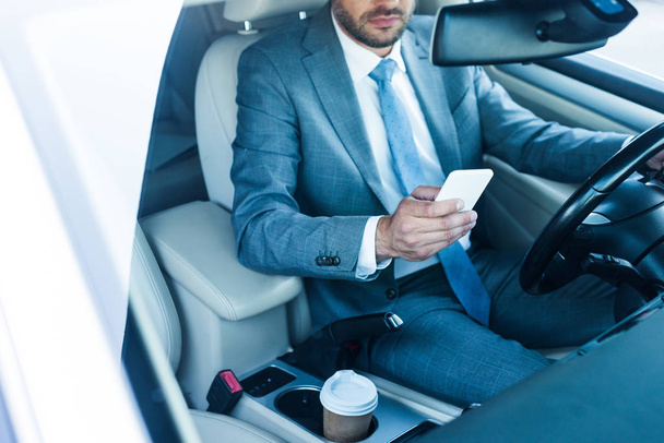 частичный взгляд бизнесмена, использующего смартфон в автомобиле
  - Фото, изображение