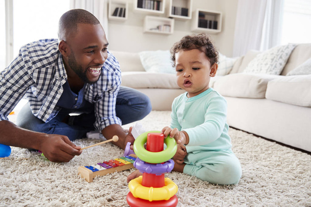 Musta isä ja lapsi poika leikkivät lattialla kotona
 - Valokuva, kuva