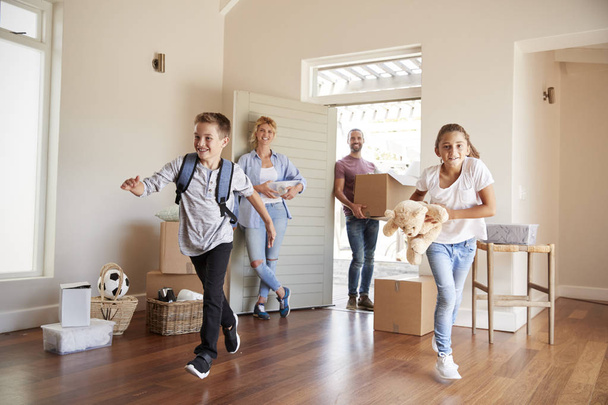 Excited Family Carrying Boxes Into New Home On Moving Day - 写真・画像