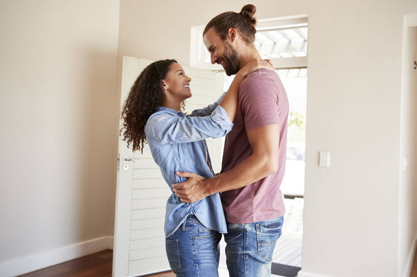 Excited Couple Hugging By Open Front Door In Lounge Of New Home - Фото, зображення