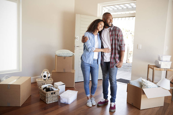 Happy Couple Surrounded By Boxes In New Home On Moving Day - Фото, изображение