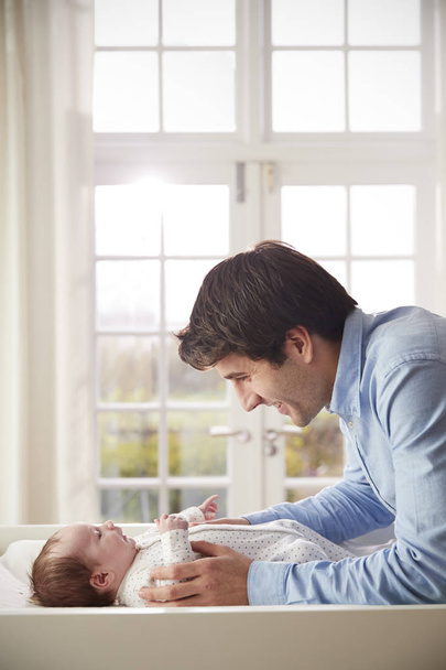 Father Playing With Newborn Baby Lying On Changing Table - Foto, immagini