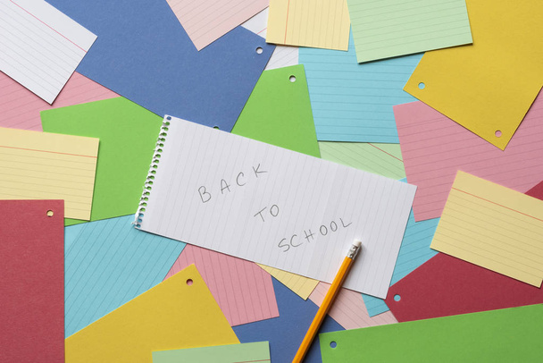 カラフルな紙のノートの背景に学校に戻るメッセージを持つノートブック シート - 写真・画像