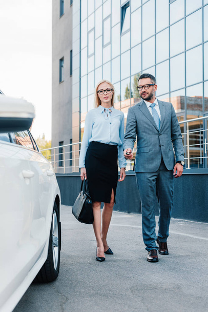 business people in eyeglasses walking to car on parking - Фото, изображение