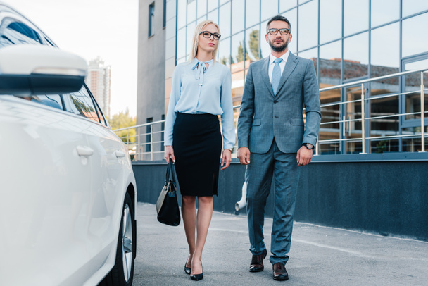 business people in eyeglasses walking to car on parking - Foto, afbeelding