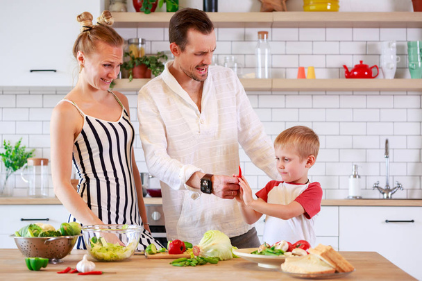 Kuva nuoresta äidistä, isästä ja pienestä pojasta valmistamassa ruokaa keittiössä
 - Valokuva, kuva
