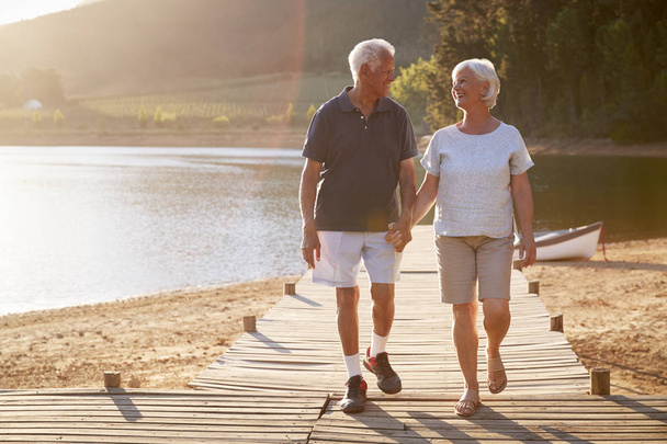 Romantisches Seniorenpaar spaziert auf Holzsteg am See - Foto, Bild