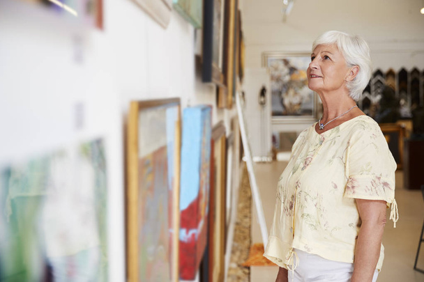 Senior Woman Looking At Paintings In Art Gallery - Foto, immagini