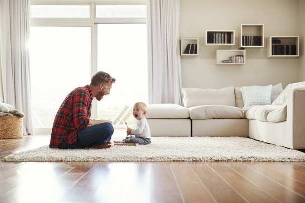 Young father and son playing together in sitting room - Photo, image