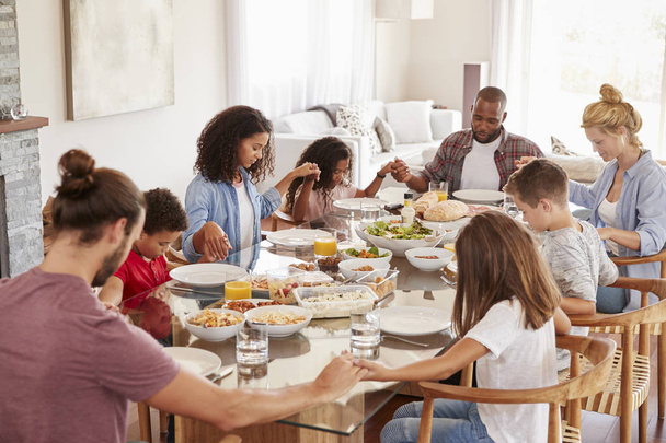 Two Families Praying Before Enjoying Meal At Home Together - Foto, imagen