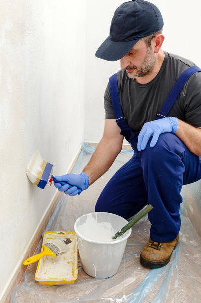 Painter paints the wall with the tint of white. Wall with serious moisture problems. Detail of the brush. white dye is prepared for the painter's job. - Photo, Image