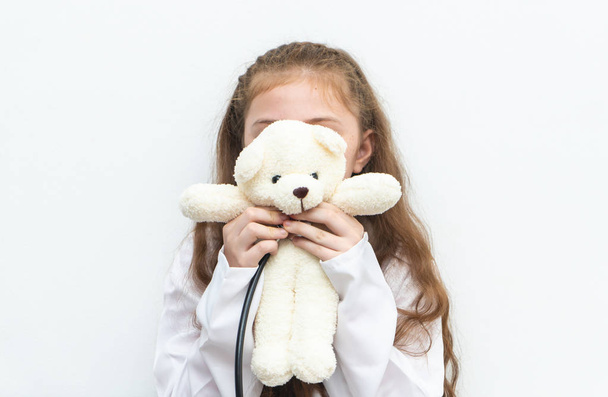 Little kid playing nurse doctor with teddy bear - Fotó, kép