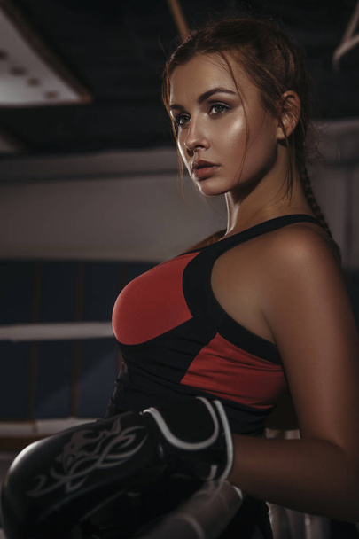 Fit slim young beautiful brunette woman boxing in sportswear. Dark dim light. Toned image - Fotografie, Obrázek