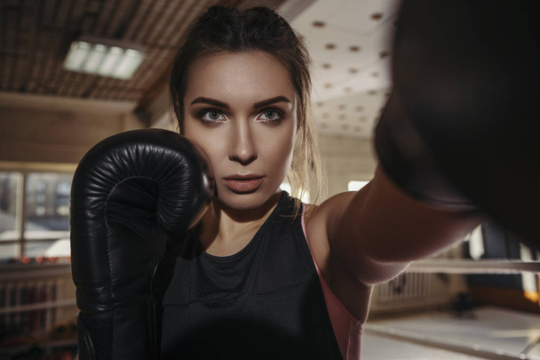 Fit slim young beautiful brunette woman boxing in sportswear. Dark dim light. Toned image - Photo, Image