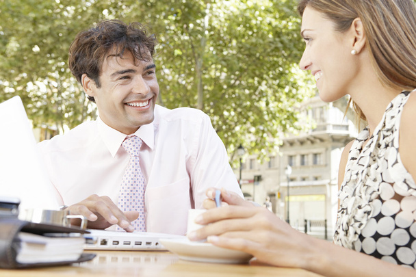 Dos negocios teniendo una reunión en una cafetería al aire libre en la ciudad, sonriendo
. - Foto, imagen