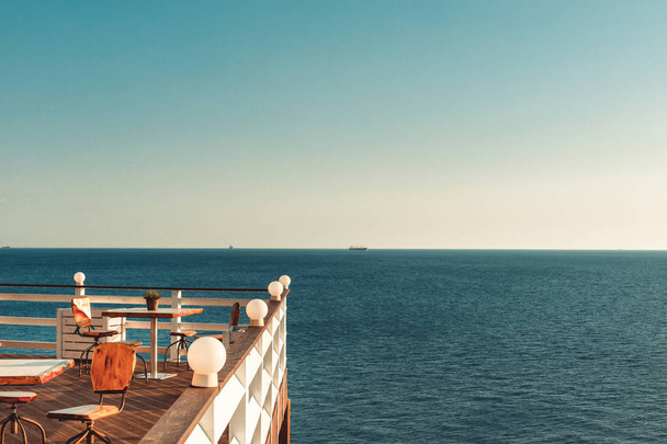 海で休んでいます。テーブルと海の美しい景色をバルコニーに木製の椅子。レクリエーション リゾート コンセプト - 写真・画像