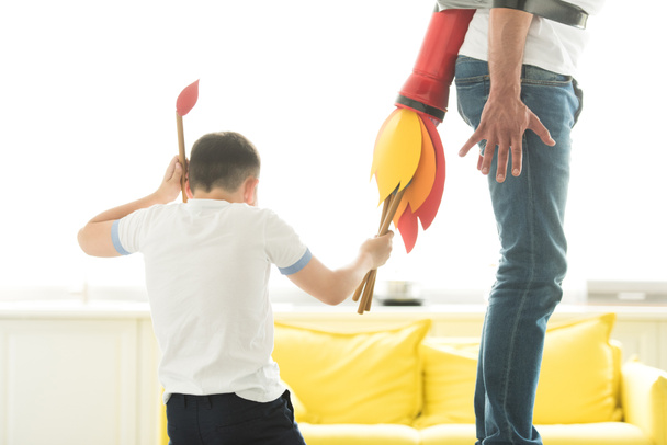 обрезанный образ непослушного сына, играющего со связанным отцом с ракетной игрушкой дома
 - Фото, изображение