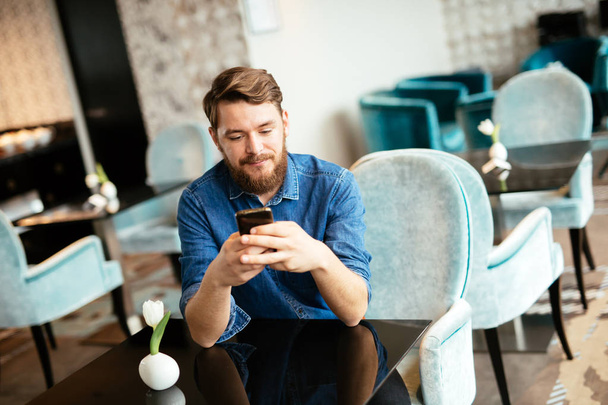 Man waiting for woman in restaurant and checking phone - Photo, image