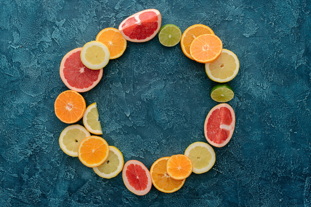 top view of round frame made of citrus fruits slices on blue concrete surface - Photo, Image