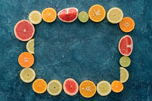 top view of frame made of citrus fruits slices on blue concrete surface - Photo, Image