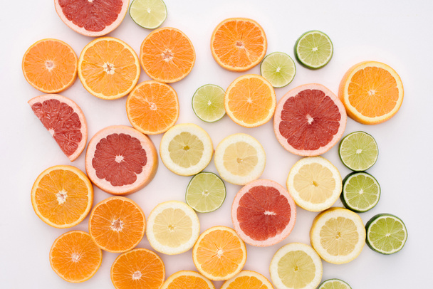 top view of various citrus fruits slices spilled on white surface - Fotó, kép