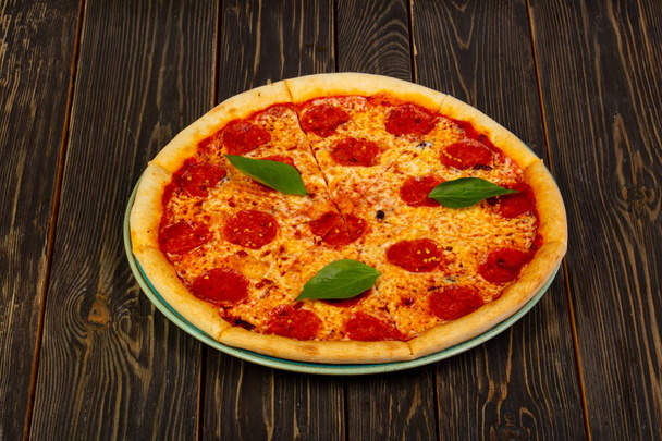 Chili-Pizza serviert Basilikumblätter - Foto, Bild
