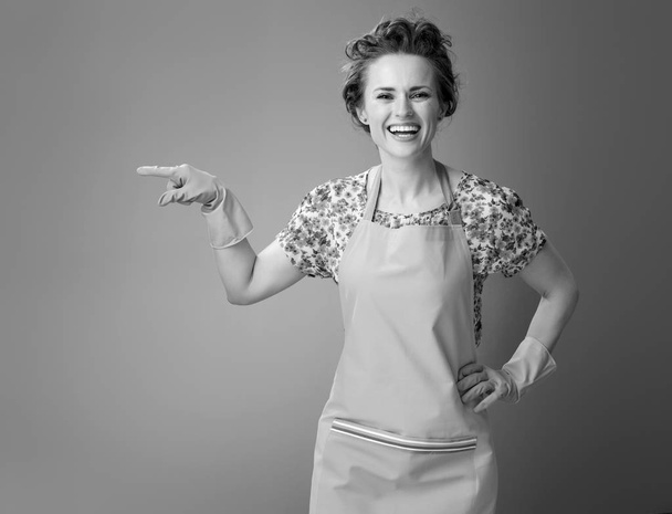 happy modern housewife in a apron pointing at something  - Фото, изображение