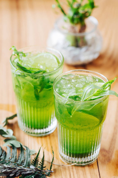 Green lemonade with tarragon, lime and ice on wooden background - Fotoğraf, Görsel